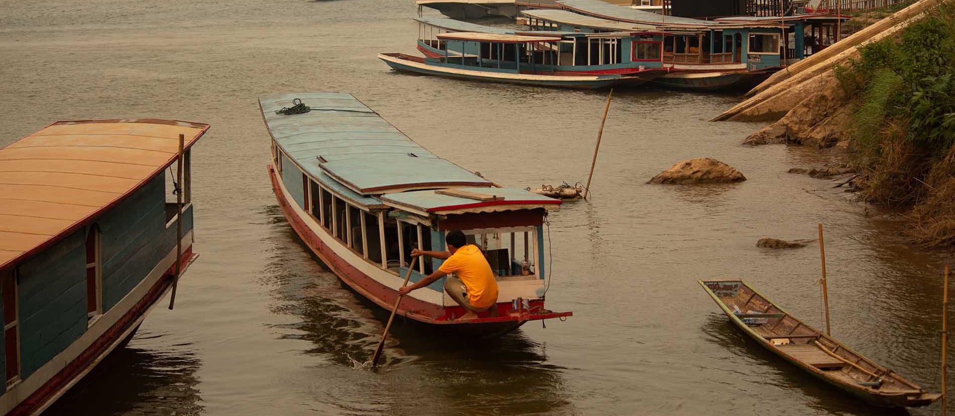 missing image A man at the end of his longtail boat, pushing with a paddle to get out into the Mekong river. The picture had been taken in Lunag Prabang, Laos