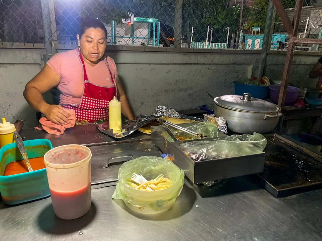 The best pupusas and quesadillas on Caye Caulker Lady with apron sorting her kitchen top at a street food stall