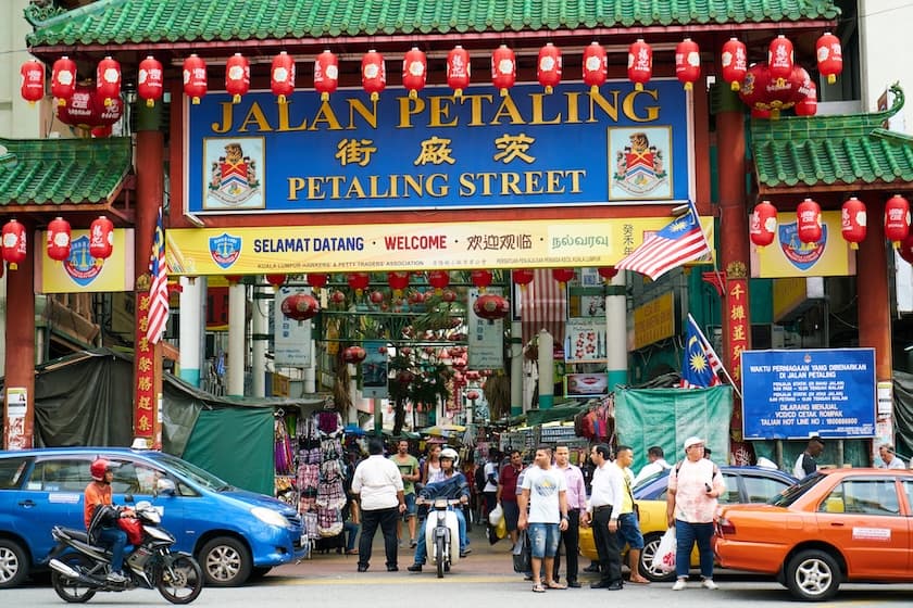Entrance of Chinatown, Kuala Lumpur / <a href="https://www.freepik.com/free-photo/entrance-chinatown_1014050.htm#page=2&query=malaysia&position=27&from_view=search&track=sph">Image by freestockcenter</a> on Freepik Entrance to Chinatown, Kuala Lumpur. The photo highlights the traditional arch with Chinese architecture. The arch is red, with the roof colored green. Around the edge of the ceiling, many Chinese lanterns are hung, also red in color. Under the arch, there are many people of various ethnicities.