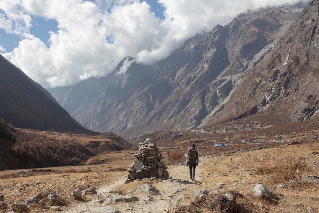missing image Between Langtang village and Kyanjin Gumpa the valley looks vast. Pauline is ahead of me walking next to the Mani stone wall, there are clouds in the sky.