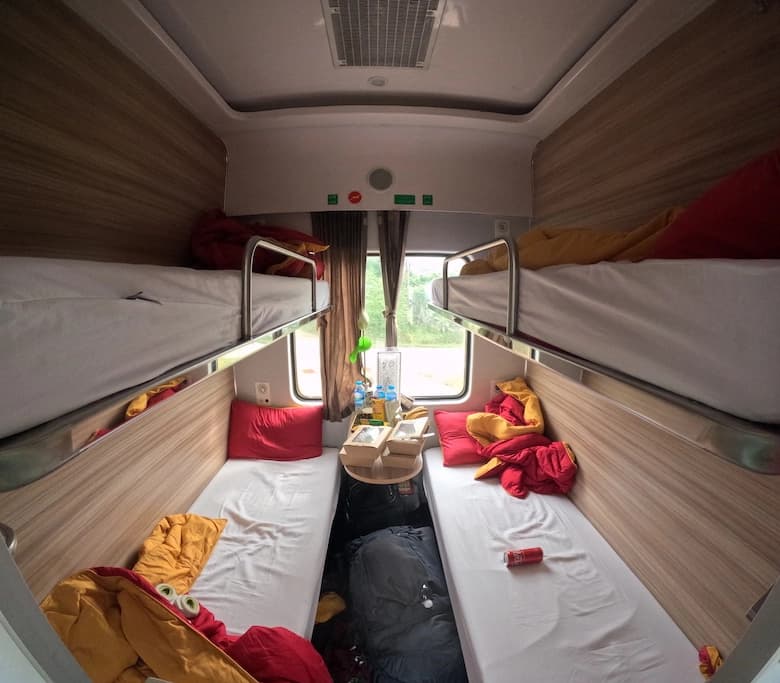 Interior of couchette of my train (the right one) from Ninh Binh to Huế, Vietnam Interior of couchette of my train (the right one) from Ninh Binh to Huế, Vietnam. The couchette contains four bunk bed, with the beds unmade as the picutre is taken in the morning. In the middle it's possible to see a little window with some green plants outside. The window is partially covetrd by curtains